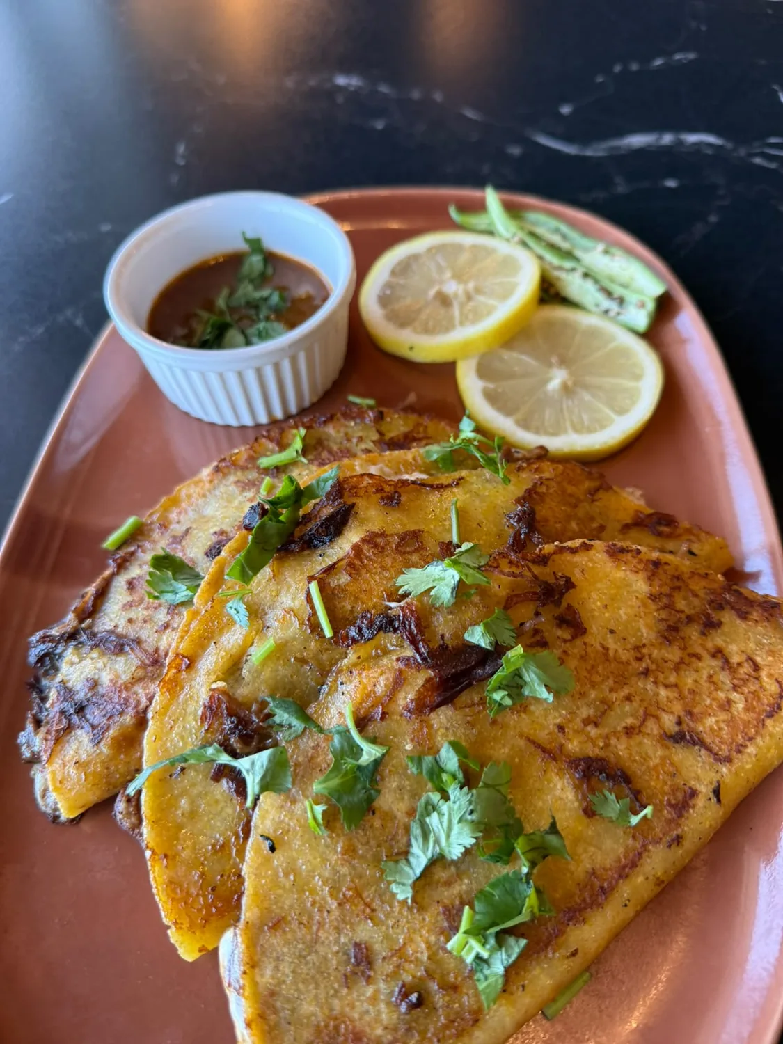 Nihari Tacos served with dipping sauce, lemon, and grilled chillies